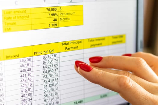 Close up shot of the woman with beautiful hands and manicure, working on the laptop, scrolling touch screen with mortgage loan amortization table open