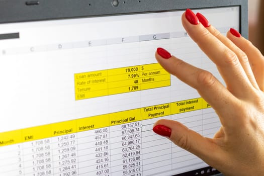 Close up shot of the woman with beautiful hands and manicure, working on the laptop, scrolling touch screen with mortgage loan amortization table open