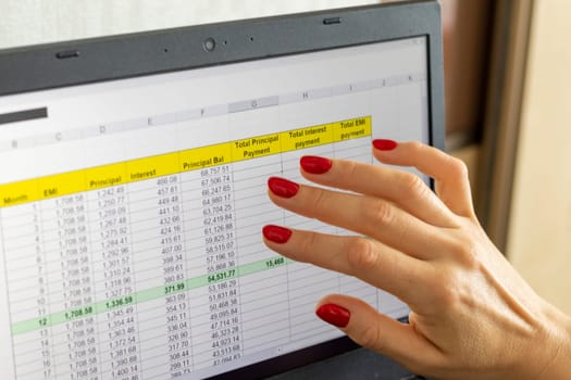 Close up shot of the woman with beautiful hands and manicure, working on the laptop, scrolling touch screen with mortgage loan amortization table open