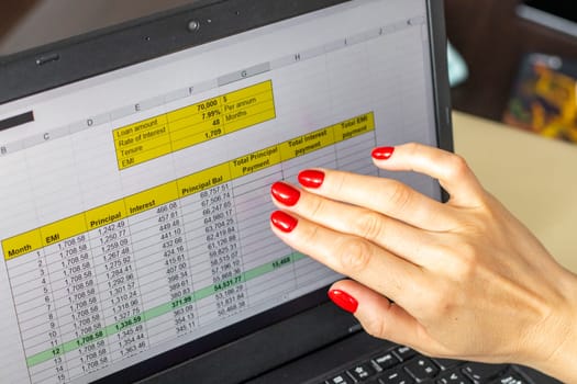 Close up shot of the woman with beautiful hands and manicure, working on the laptop, scrolling touch screen with mortgage loan amortization table open