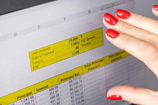 Close up shot of the woman with beautiful hands and manicure, working on the laptop, scrolling touch screen with mortgage loan amortization table open