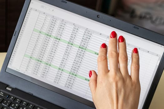 Close up shot of the woman with beautiful hands and manicure, working on the laptop, scrolling touch screen with mortgage loan amortization table open