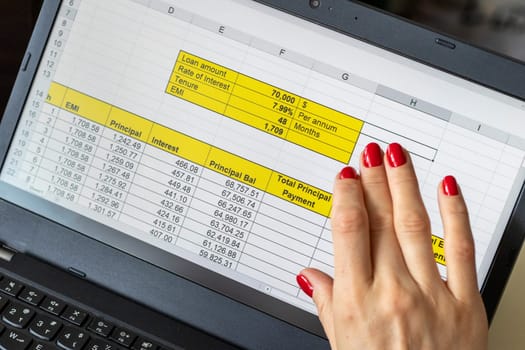 Close up shot of the woman with beautiful hands and manicure, working on the laptop, scrolling touch screen with mortgage loan amortization table open