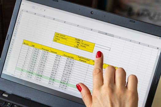 Close up shot of the woman with beautiful hands and manicure, working on the laptop, scrolling touch screen with mortgage loan amortization table open