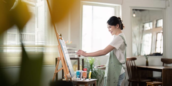 A dedicated artist painting on a canvas in a bright, modern workshop filled with natural light, showcasing creativity and artistic expression.