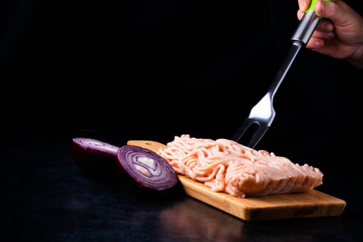 Minced meat on wood with fork. Fashionable photo of minced meat with space for text.