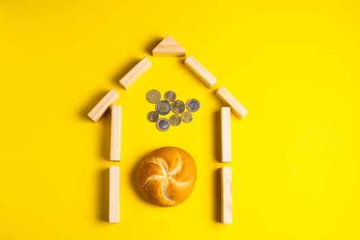 Hand holding money coins close to bread on a yellow background