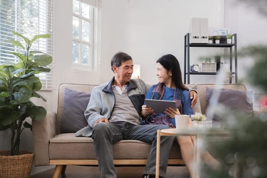 Elderly couple relaxing on a sofa in a modern living room, enjoying quality time together with a tablet. Cozy home environment with natural light and minimalist decor.