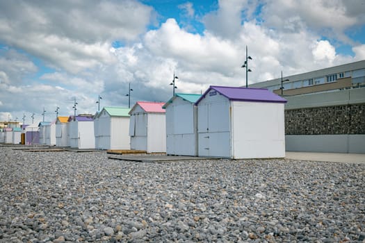wooden beach houses with different colored roofs on the beach of le treport in France Normandy with a cloudy sky as a background
