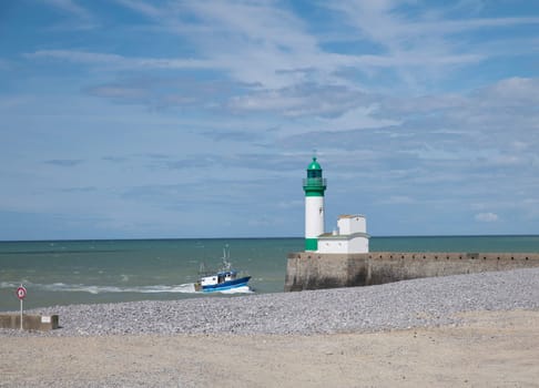 Le Treport lighthouse Seine Maritime, Normandy, France with the beach as foreground and and a fishing boat