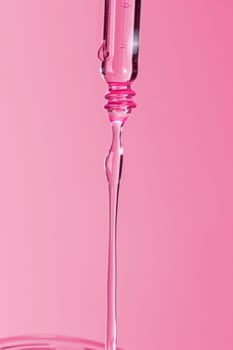 Pink liquid dripping from a syringe on a pink background for medical and health concept