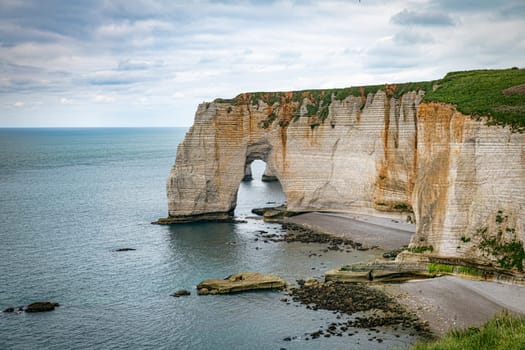 Landscape photo of tall, steep limestone cliffs by the ocean with one with a hole in it creating an arch