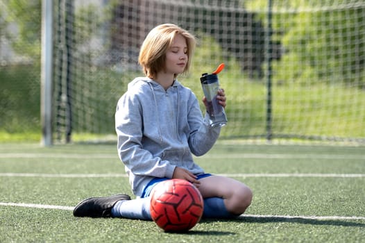 Girl In Football Uniform Sits Tossing Ball On Football Field