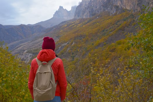 Brunette woman with a backpack on her back outdoors exploring the Caucasus Mountains in Russia, traveling, lifestyle, hiking, active autumn holidays, hiking.