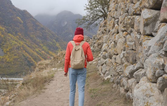 A free woman traveler walks along paths in the mountains on a foggy autumn day. Adventure travel and success concept.