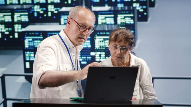 Octogenarian employees looking around innovative server hub, preparing to start comission on malfunctioning high tech space hardware cabinets in order to ensure smooth operations