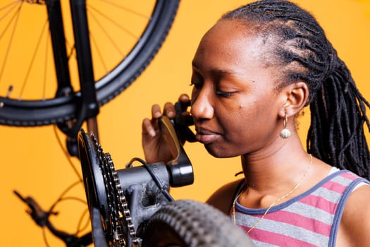 Photo focus on black lady inspecting the chain stay of her bicycle for optimum pedaling. Sporty woman in close-up, demonstrates her attention to detail as she meticulously maintains her bicycle parts.