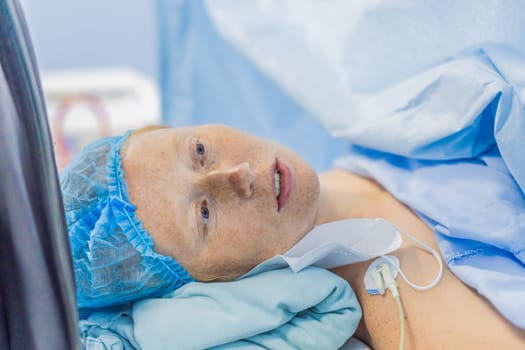 A woman lies in the operating room, ready for surgery. Surrounded by advanced medical equipment and healthcare professionals, she exhibits calmness and trust, highlighting the importance of the procedure.