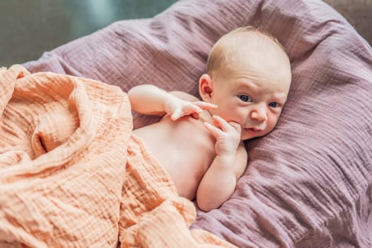 A newborn lies in his cozy cocoon on muslin swaddles. This serene moment captures the comfort and security of a newborn, highlighting the gentle care and nurturing environment.