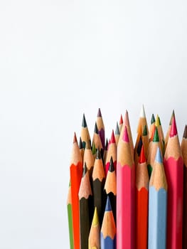 Assorted sharpened colorful pencils pointing up on white background with copy space for text. Concept of artistic or school supplies for design, teaching and educational purposes. High quality photo