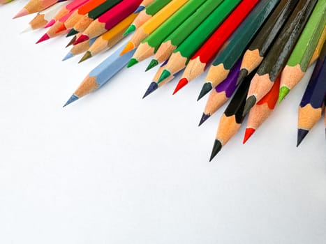 Diagonal arrangement of sharp multi colored pencils on white background with empty space for text. Artistic concept for stationery, education, design or advertising banner for school products.