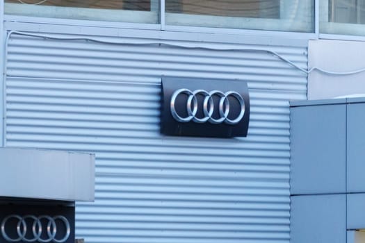 Tyumen, Russia-March 18, 2024: Audi Brand Logo on Gray Textured Wall, close up.