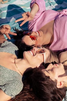 Group of girls on the beach wearing sunglasses lying on their backs on their summer vacation