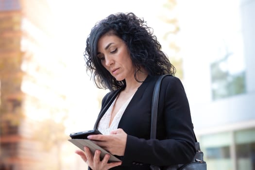 Portrait of a smiling middle-aged business woman with digital tablet in serious hands