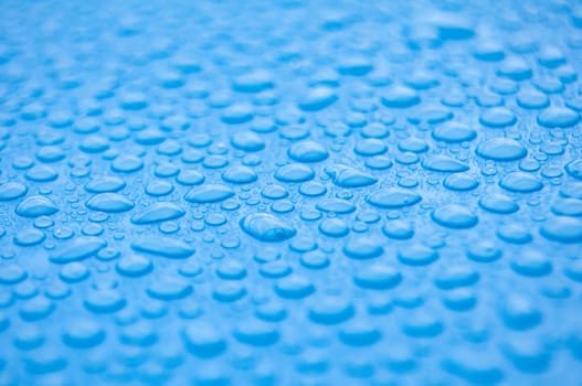 Close up side view of water droplets on blue background.
