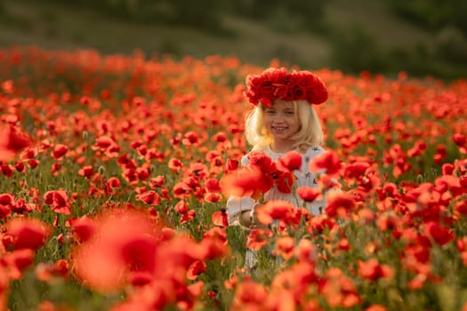 A young girl stands in a field of red poppies. She is wearing a red headband and a white shirt