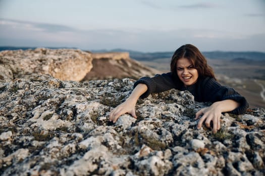 Fear of heights woman climbing rock with hands on face and mouth open