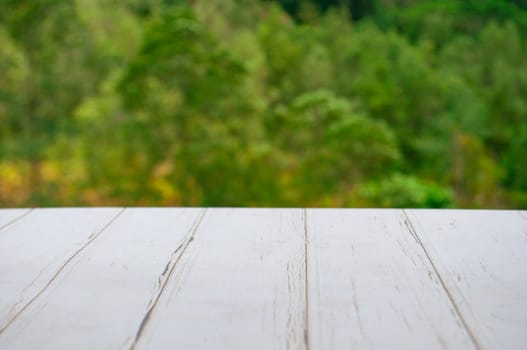 Empty wooden table in front of blurred nature background with customizable space for display or montage your products.