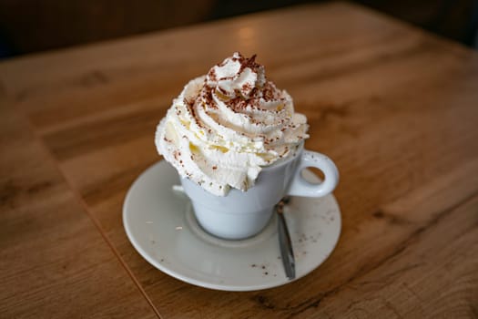 a large cup of cappuccino with lots of whipped cream and chocolate served in a cup in a restaurant