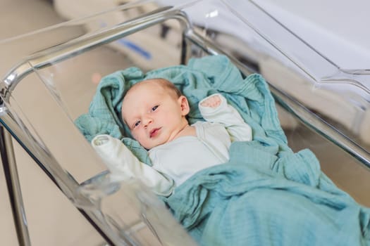 A newborn rests peacefully in his transparent bassinet in the hospital. The clear bassinet provides visibility for medical staff to monitor the baby's well-being while ensuring a safe and comfortable environment for the newborn.