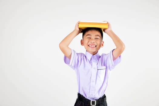 Portrait smiling Asian little boy primary posing holding book over head and screaming studio shot isolated white background, happy cute man kid wear school uniform pride, back to school concept