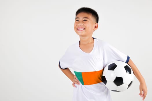 Portrait Asian smiling young boy kids wear uniform holding soccer ball and looking up to space studio shot isolated white background, cute child playing football sport hobby for kids, leisure games