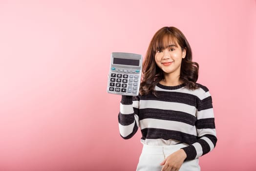 Tax day concept. Woman confident smiling holding electronic calculator, Portrait excited happy Asian young female studio shot isolated on pink background, Business Account and finance counting income