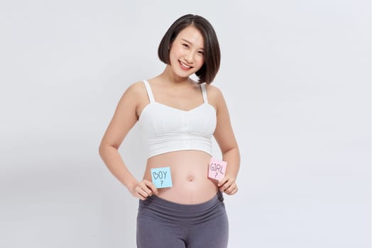 Belly of a young pregnant woman with a white sticker and a question on it (boy or girl concept)