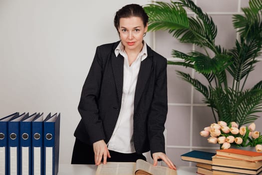 the female director in office stands at the desk with the book in the office