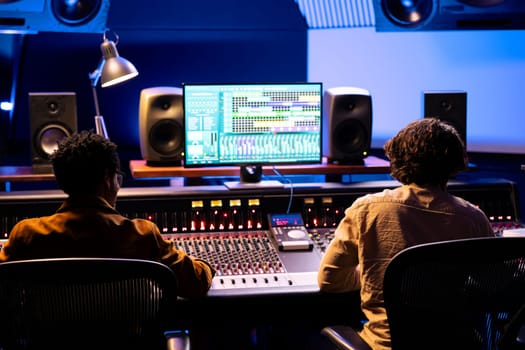 Team of singer and composer working on track recording in studio, editing and processing music in control room with technical gear. Musician and audio engineer producing tunes for an album.