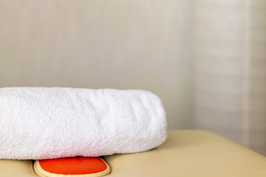 Close up shot of the white towels rolled in the massage couch