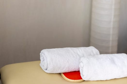 Close up shot of the white towels rolled in the massage couch