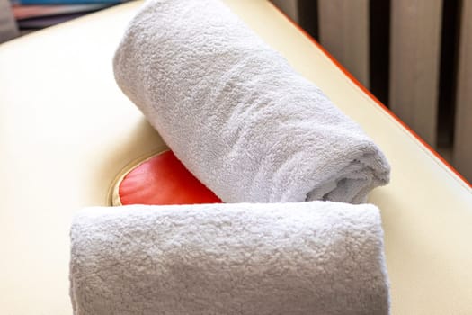 Close up shot of the white towels rolled in the massage couch.