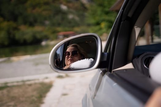 A blonde woman in a white sweater and jeans is driving. Happy woman sitting in the car