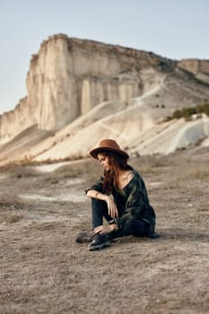 Woman wearing hat sitting in front of majestic mountain peak