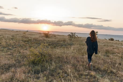 solitude and serenity woman walking through sunset field towards ocean horizon