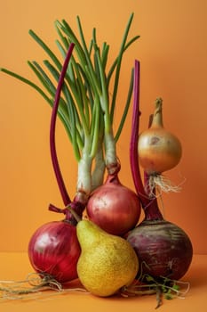 Fresh produce assortment of red, yellow, and green onions and a juicy pear on bright orange background