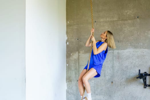 Horizontal photo with copy space of a fit young woman climbing a rope as her exercise training