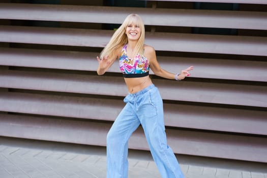 Blonde happy young woman dancing freestyle alone in the street