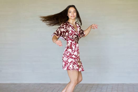 Joyful beauty caucasian female dancer turning energetically and smiling at camera in the city